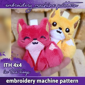 May include: Two plush fox toys, one pink and one yellow, are held in a hand. The toys are designed for embroidery machine projects and are labelled "ITH 4x4 in the hoop embroidery machine pattern".