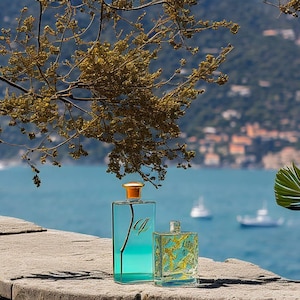May include: Two glass bottles of perfume, one blue and one gold, sitting on a stone surface with a view of a body of water and a green hillside in the background.