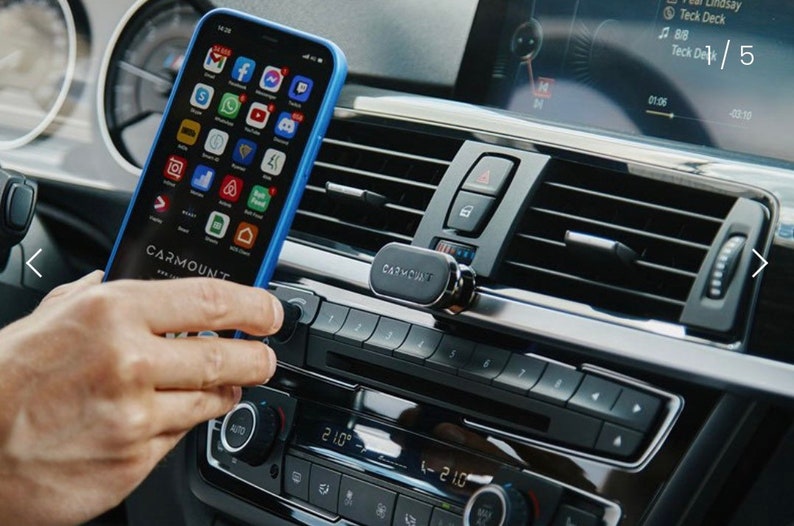 May include: A black magnetic phone mount attached to a car's air vent. A blue phone case with a smartphone inside is held in place by the mount. The phone screen displays various app icons.