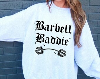 May include: A grey sweatshirt with the text "Barbell Baddie" in black gothic font and a black barbell graphic.