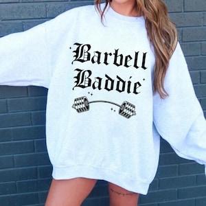 May include: A grey sweatshirt with the text "Barbell Baddie" in black gothic font and a black barbell graphic.