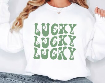 May include: White sweatshirt with a green graphic of the word "LUCKY" repeated three times. Each letter is decorated with a shamrock.