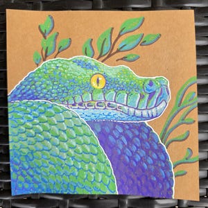 May include: A detailed illustration of a snake with a green and blue color scheme. The snake's scales are meticulously rendered, and it has a yellow eye. Green leaves are depicted around the snake's head, set against a brown background.