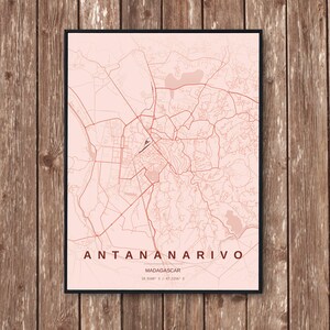 Könnte beinhalten: Ein gerahmter Kartendruck von Antananarivo, Madagaskar, in Rosa- und Rottönen. Die Stadtkarte zeigt detaillierte Umrisse von Straßen und Sehenswürdigkeiten. Der Text "ANTANANARIVO" ist unten mit dem Ländernamen und den Koordinaten abgebildet.