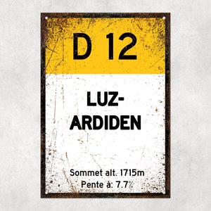 以下が含まれることがあります： 「D 12 LUZ-ARDIDEN」と「Sommet alt. 1715m Pente à: 7.7%」のテキストが書かれた黄色と白の金属製の標識です。
