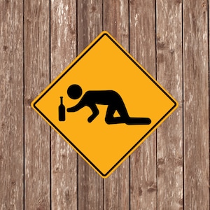 Könnte beinhalten: Ein gelbes Warnschild mit einer schwarzen Silhouette einer Person, die mit einer Flasche in der Hand auf dem Boden kriecht. Das Schild befindet sich auf einem hölzernen Hintergrund.