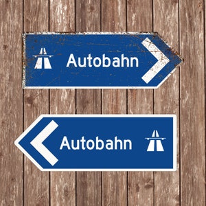 May include: Two blue and white signs with white arrows pointing in opposite directions. The signs read "Autobahn" and feature a white highway symbol.