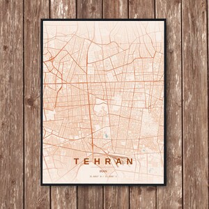 May include: A framed map print of Tehran, Iran, in a warm, earthy color palette. The city map features detailed street layouts and is labeled with the city name and country. The print is set against a wooden background.