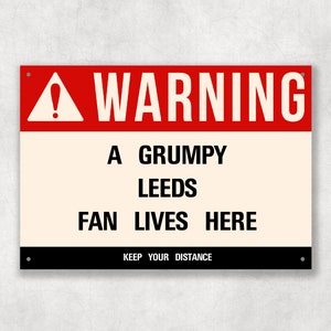 Puede incluir: Un cartel de advertencia rojo y blanco con un signo de exclamación negro. El cartel dice "WARNING A GRUMPY LEEDS FAN LIVES HERE KEEP YOUR DISTANCE".