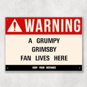 Op de afbeelding: Een rood en wit waarschuwingsbord met een zwart uitroepteken. Het bord luidt "WARNING A GRUMPY GRIMSBY FAN LIVES HERE KEEP YOUR DISTANCE".