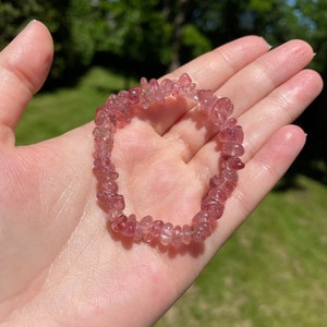 Peut inclure: Un bracelet en cristal rose et transparent. Le bracelet est composé de petites plaquettes de cristal de forme irrégulière. Le bracelet est enfilé sur un cordon élastique transparent.