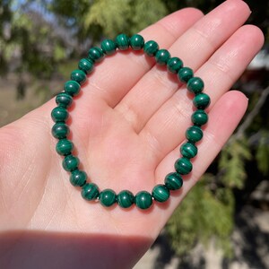 May include: A green malachite beaded bracelet. The beads are round and have a natural, striated pattern.