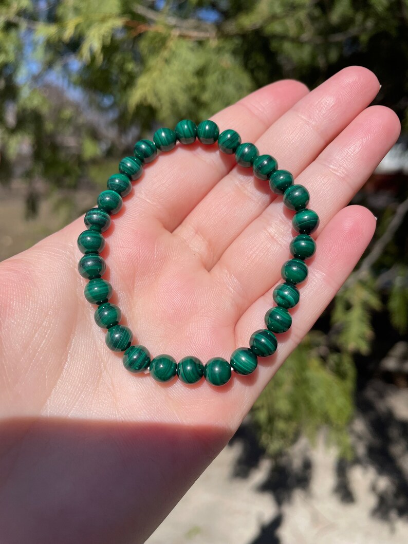 May include: A green malachite beaded bracelet. The beads are round and have a natural, striated pattern.