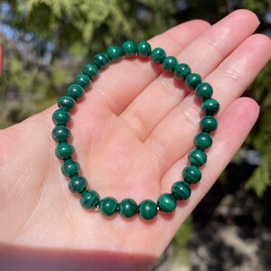May include: A green malachite beaded bracelet with a dark green and light green marbled pattern.