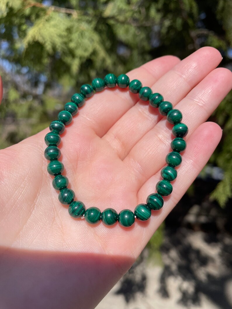 May include: A green malachite beaded bracelet with a dark green and light green marbled pattern.