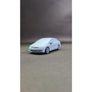 May include: White model car with a detailed front grille and headlights. The car is a saloon with four doors and a black interior.