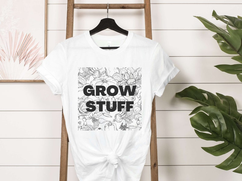 May include: White t-shirt with a black and white floral design and the text "GROW STUFF" printed on the front.