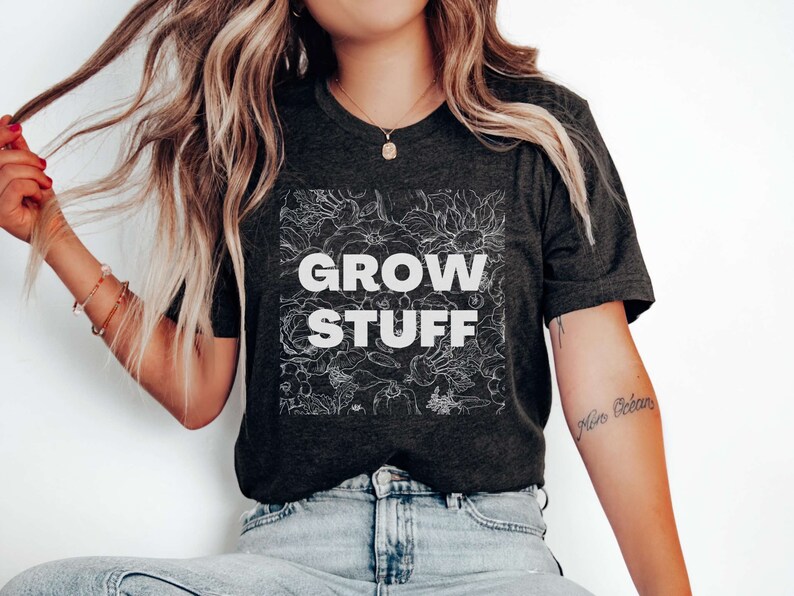 May include: A dark gray t-shirt with a white floral design and the text "GROW STUFF" in white.