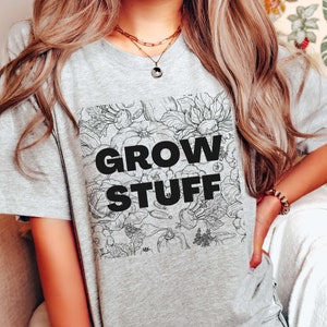 May include: Gray t-shirt with a black and white floral design and the text "GROW STUFF" printed on the front.