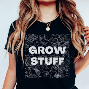 May include: Black t-shirt with a white floral design and the text "GROW STUFF" in white.