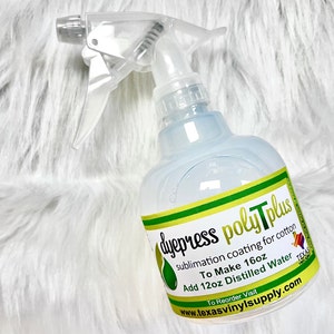 May include: A clear plastic spray bottle with a white trigger and a label that reads "dyepress poly Tplus sublimation coating for cotton." The bottle is on a white, fluffy surface. The label also says "To Make 16oz" and "Add 12oz Distilled Water."