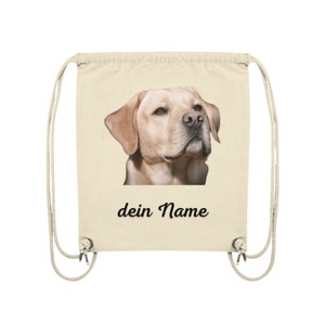 May include: A beige drawstring bag with a picture of a golden retriever dog on the front. The text "dein Name" is printed below the image.