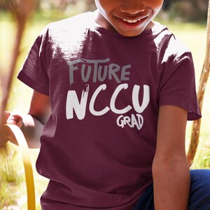 May include: A maroon t-shirt with white text that reads "Future NCCU Grad".