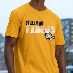 May include: A yellow t-shirt with the words "Stillman Tigers" in navy blue and white lettering. A navy blue and gold tiger head graphic is below the text.