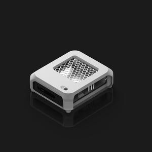 Peut inclure: Un appareil &eacute;lectronique blanc et gris avec un &eacute;vent en nid d'abeille sur le dessus. L'appareil a une forme rectangulaire avec des bords arrondis et plusieurs ports sur les c&ocirc;t&eacute;s. L'appareil est pos&eacute; sur un fond sombre.