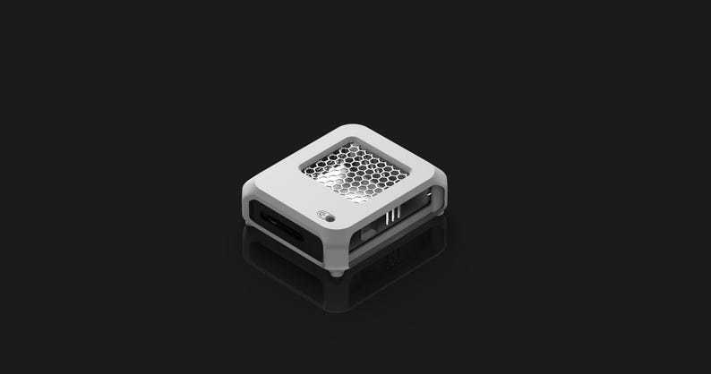 Peut inclure: Un appareil &eacute;lectronique blanc et gris avec un &eacute;vent en nid d'abeille sur le dessus. L'appareil a une forme rectangulaire avec des bords arrondis et plusieurs ports sur les c&ocirc;t&eacute;s. L'appareil est pos&eacute; sur un fond sombre.