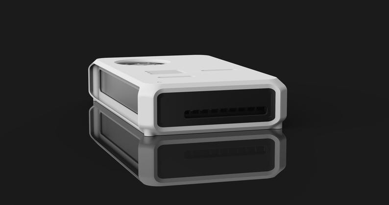 May include: A white rectangular electronic device with a black front panel and a series of vents. The device has a rounded frame and is reflected on a glossy black surface. The top has a circular opening and other small openings.