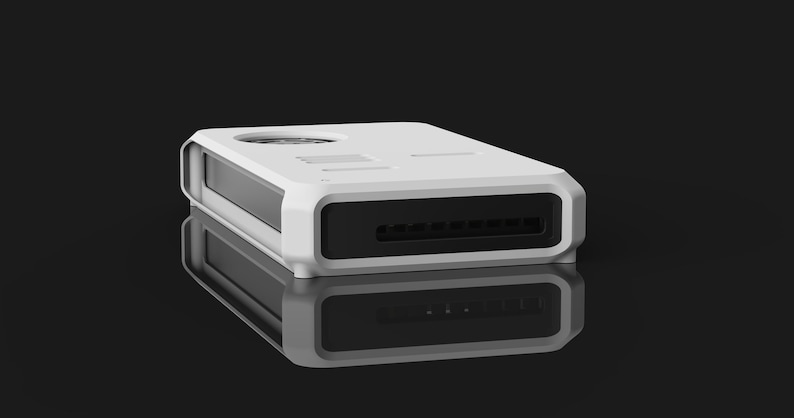 Op de afbeelding: Een wit rechthoekig elektronisch apparaat met een zwart voorpaneel en een cirkelvormige ventilatieopening aan de bovenkant. Het apparaat heeft een strak, modern ontwerp en wordt weerspiegeld op een glanzend zwart oppervlak.