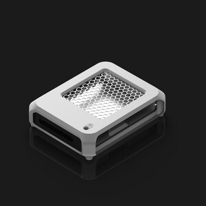 Op de afbeelding: Een wit rechthoekig elektronisch apparaat met een honingraatgaas bovenkant en een kleine knop. Het apparaat heeft een strak, modern ontwerp en staat tegen een donkere achtergrond. Het apparaat lijkt een computercomponent te zijn.