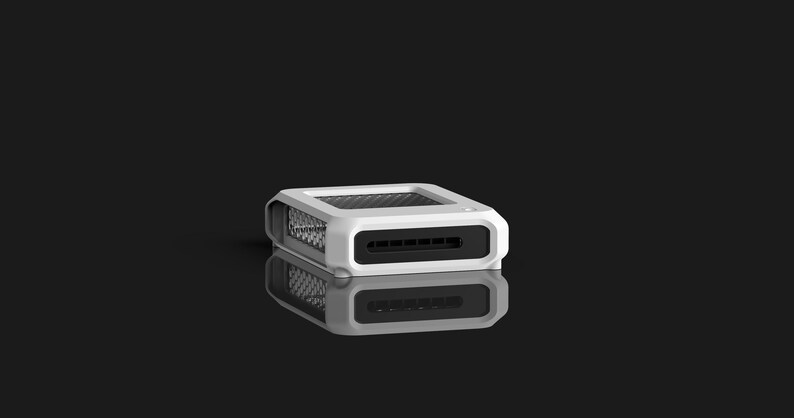 Op de afbeelding: Een wit en zwart rechthoekig elektronisch apparaat met een mesh-bovenkant en een reeks sleuven aan de voorkant. Het apparaat wordt weerspiegeld op een zwart oppervlak. Het apparaat lijkt een kleine computercomponent te zijn.