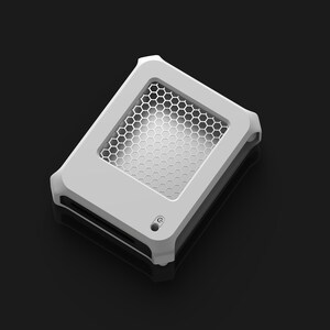 Op de afbeelding: Een wit en grijs rechthoekig apparaat met een honingraatpatroon aan de bovenkant. Het apparaat heeft afgeronde hoeken en een kleine ronde knop. De achtergrond is donkergrijs.