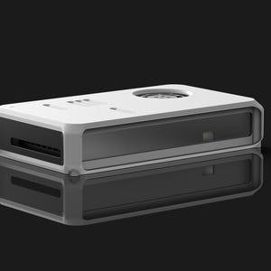 May include: A white and gray rectangular electronic device with a rounded frame. The device has a dark gray interior and a circular vent on top. The device is reflected on a black surface.