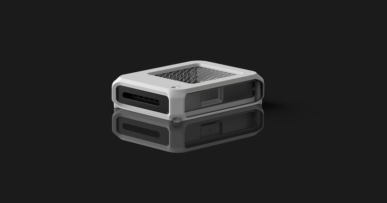 Op de afbeelding: Een wit en zwart rechthoekig elektronisch apparaat met een mesh-bovenkant en een reflecterend oppervlak eronder. Het apparaat heeft een sleuf aan de voorkant en een doorzichtig zijpaneel. De achtergrond is zwart.
