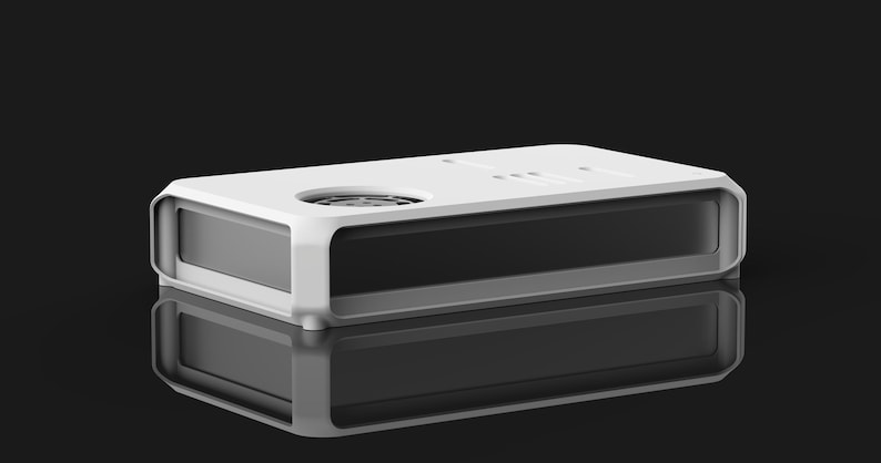 May include: A rectangular, modern-style device with a white top and a gray base. The top features a circular element and several small, rectangular indentations. The device is reflected on a glossy black surface, creating a symmetrical image.