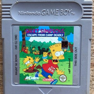 May include: A gray Nintendo Game Boy cartridge featuring the game "Bart Simpson's Escape From Camp Deadly." The label shows Bart Simpson in a red shirt with "Camp Dead" on it, running from a monster. The background is a green field with other characters.
