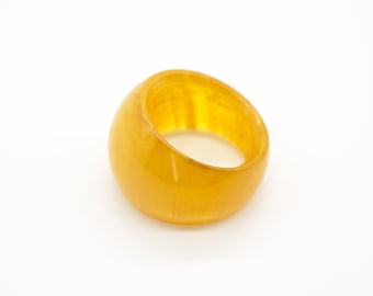 Peut inclure: Une bague en résine opaque jaune. La bague est lisse et a une finition brillante.