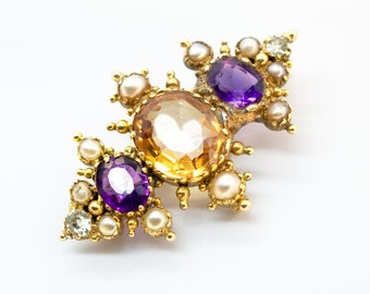 May include: A gold brooch with a large, faceted, yellow-orange gemstone surrounded by smaller pearls and two purple amethysts.