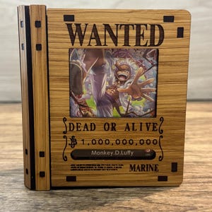 May include: A wooden display frame featuring a Wanted poster design with the text WANTED, DEAD OR ALIVE, 1,000,000,000, Monkey.D.Luffy, and MARINE. The center displays a colorful illustration of a smiling character with white hair and purple pants.