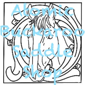 May include: A black and white line drawing of a horse's head inside a circle. The text "Atomic Buckaroo Saddle Shop" is written in a stylized font around the circle.