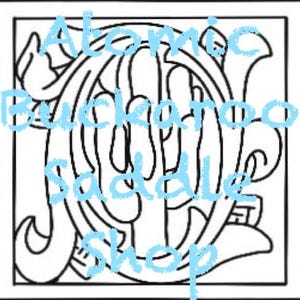 May include: Black and white line art illustration of a stylized letter J with the text "Atomic Buckaroo Saddle Shop" in blue lettering.