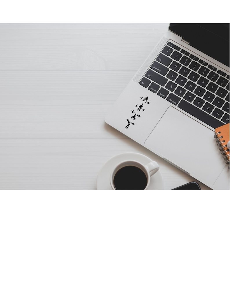 May include: A silver laptop computer with a black keyboard and trackpad. The trackpad has a series of black stick figure icons depicting different exercises. The laptop is on a white wooden surface with a cup of coffee and a notebook.