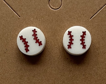May include: A pair of white stud earrings with red baseball stitching.