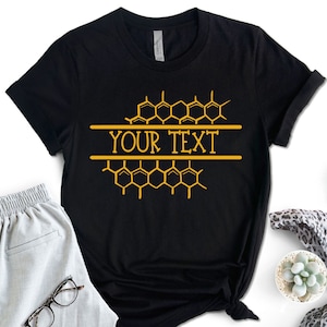 May include: Black t-shirt with a honeycomb design and the text "YOUR TEXT" in a gold color.