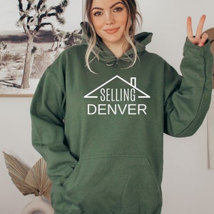 May include: A green hooded sweatshirt with a white graphic of a house with the text "SELLING DENVER" underneath.