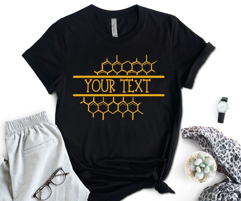K&ouml;nnte beinhalten: Schwarzes T-Shirt mit einem Wabenmuster und dem Text "YOUR TEXT" in Gold.