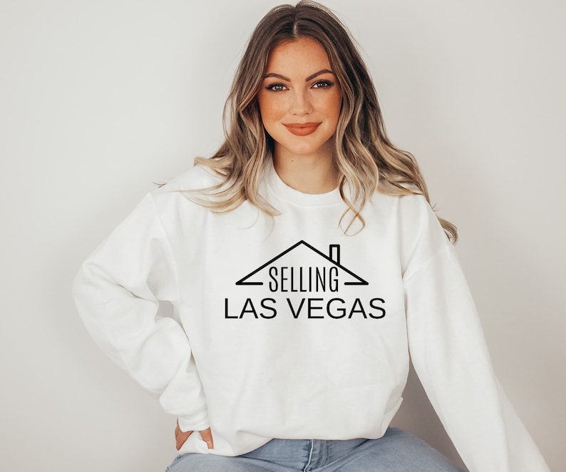 May include: White sweatshirt with black text that reads "SELLING LAS VEGAS" with a house graphic above the text.